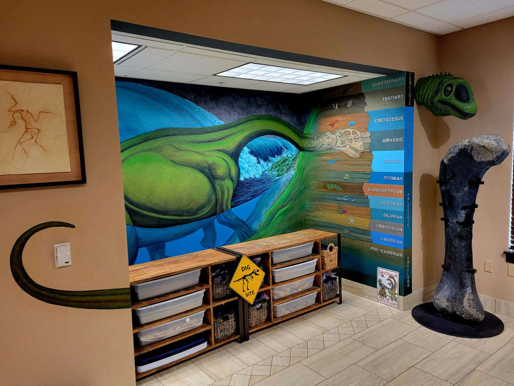 At the other end of the Creation Study Center is a dinosaur mural of a Camarasaurus. To the upper right, mounted on the wall, is the dinosaur head I painted.
